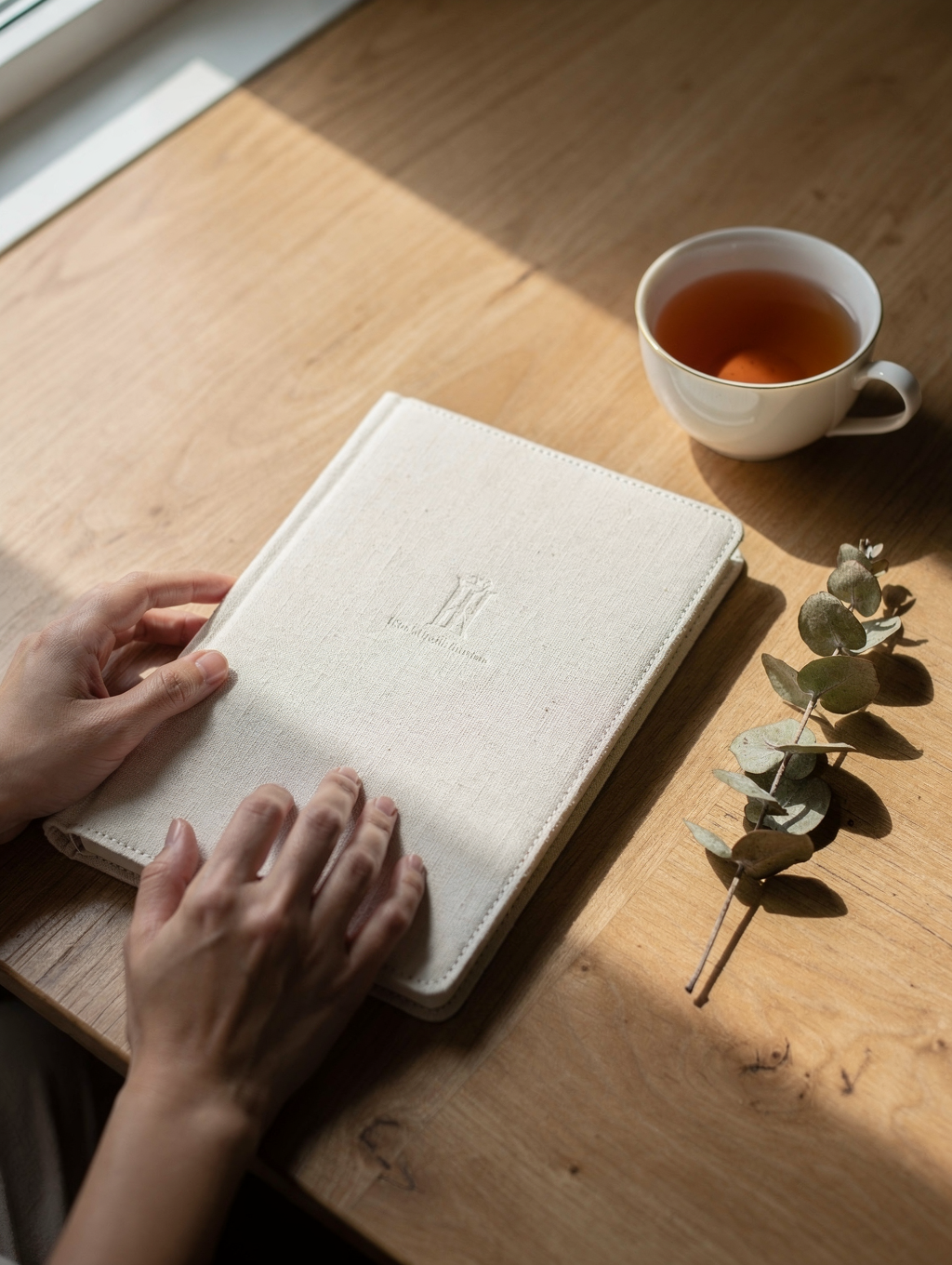 Manos escribiendo con serenidad en un cuaderno de hojas cálidas sobre una mesa de madera